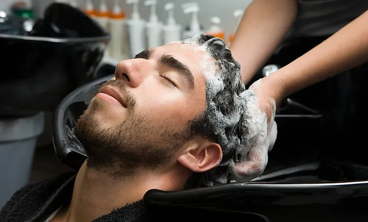 A man having his hair washed over a salon sink